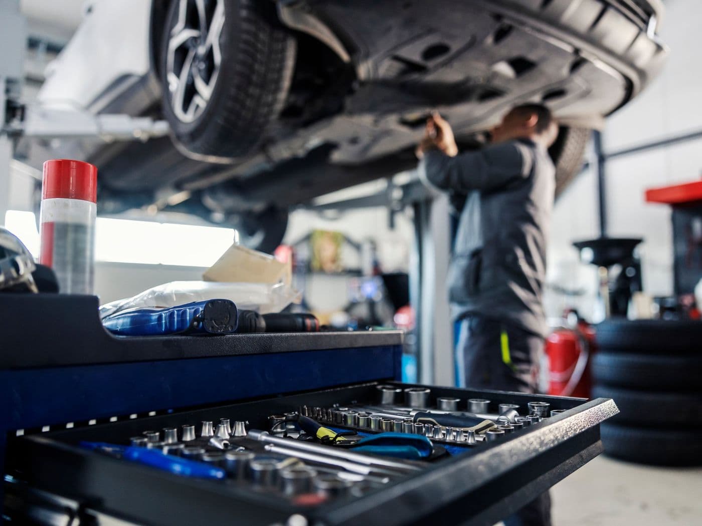 Fahrzeug auf der Hebebühne in unserer Werkstatt, im Vordergrund ein Werkzeugwagen